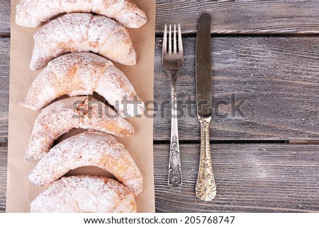 Tasty bagels with sugar powder, on wooden background