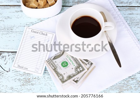 Check, money and cup of coffee on table close-up