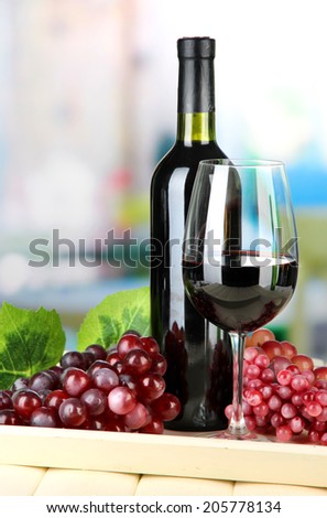 Ripe grapes, bottle and glass of wine on tray, on bright background