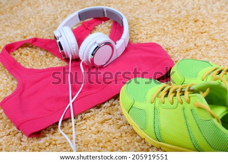 Sport clothes, shoes and headphones on color carpet background.