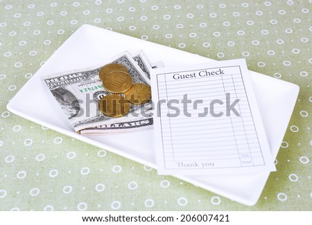 Check and money on tray on table close-up