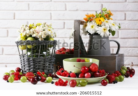 Still life with berries and flowers on white wall background