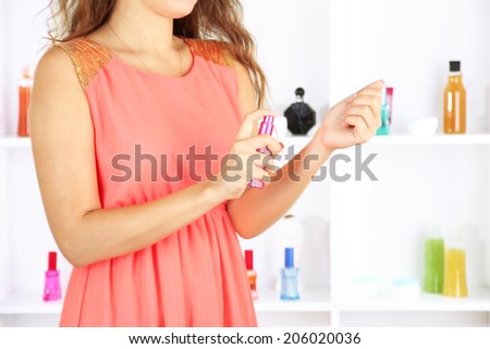 Woman testing perfume on shop windows background