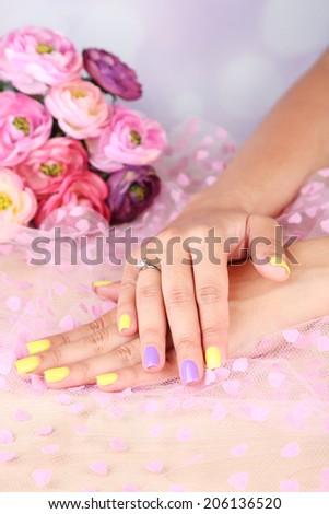 Female hand with stylish colorful nails, on color fabric background