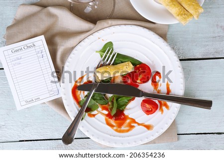 Check and remnants of salad on table in restaurant