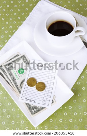Check, cup of coffee and money on table close-up