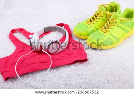 Sport clothes, shoes and headphones on white carpet background.