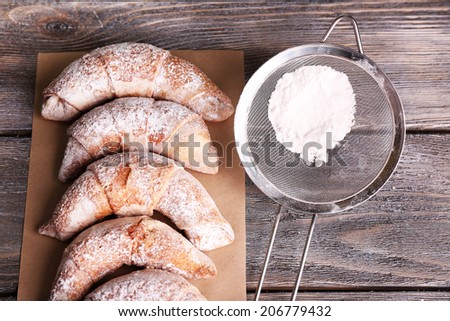 Tasty bagels with sugar powder, on wooden background