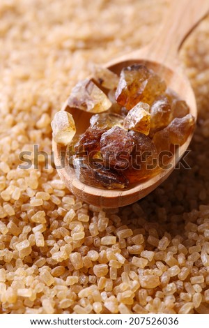 Reed sugar in wooden spoon on brown crystal sugar background