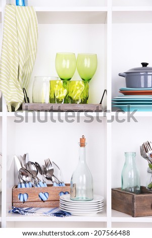 Kitchen utensils and tableware on beautiful white shelves