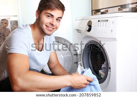 Housework: Man loading clothes into washing machine