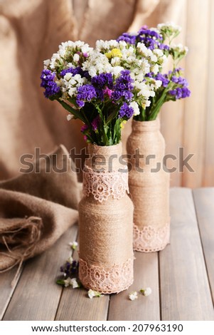 Beautiful bouquet of bright flowers in vase on table on brown background