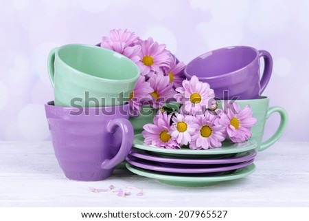 Bright dishes with flowers on table on bright background