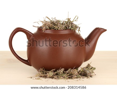 Dried herbs in teapot on wooden table, isolated on white. Conceptual photo of herbal tea.