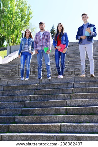 Happy students on stairs in park