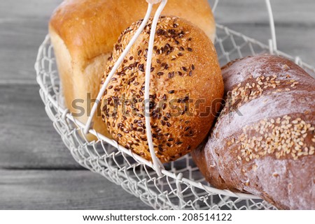 Fresh baked bread in basket, on wooden background