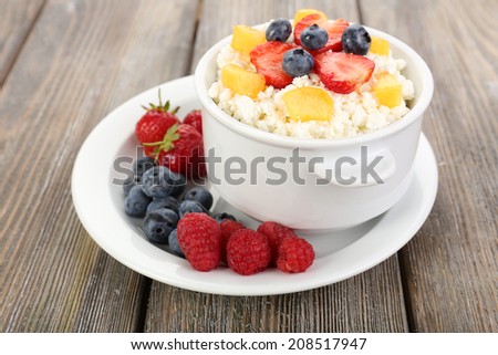 Cottage cheese with fruits and berries in bowl on wooden table