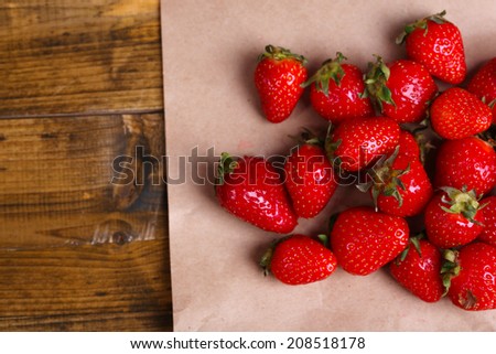 Ripe sweet strawberries  on paper napkin on color wooden background