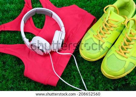 Sport clothes, shoes and headphones on green grass background