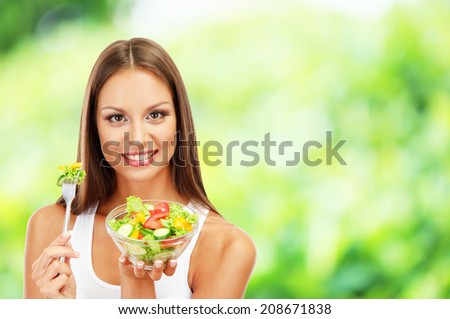 Beautiful young woman with salad on nature background