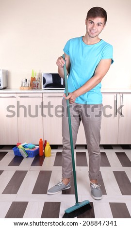 Young man cleaning floor in room