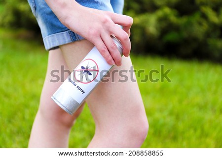 Woman spraying insect repellent on skin, outdoor