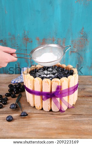 Tasty cake Charlotte with blueberries and sugar powder, on wooden table