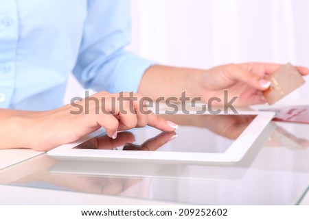 Woman using digital tablet and holding credit card in her hand, close-up. On-line shopping concept
