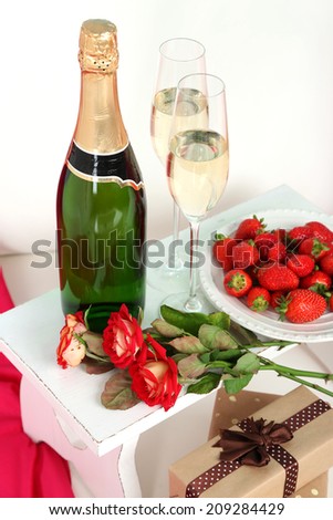 Romantic still life with champagne, strawberry and roses on sofa