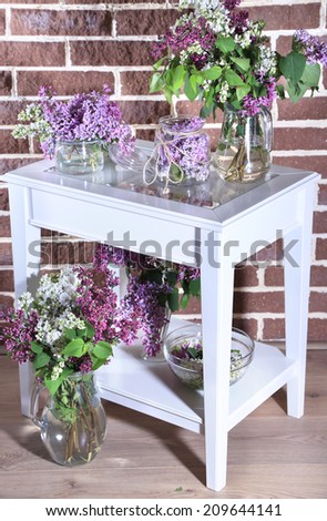 Beautiful lilac flowers in vase, on table, on color wall background
