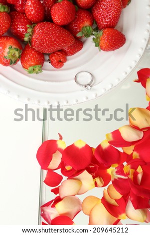 Romantic still life with strawberry, ring and petals of roses roses close-up