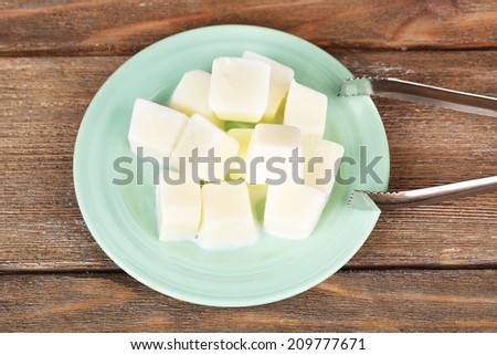 Milk ice cubes on plate on wooden background
