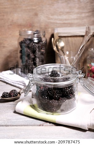 Sweet blackberries in glass jar on  wooden background