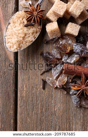 Brown sugar cubes, reed and crystal sugar, spices on wooden background