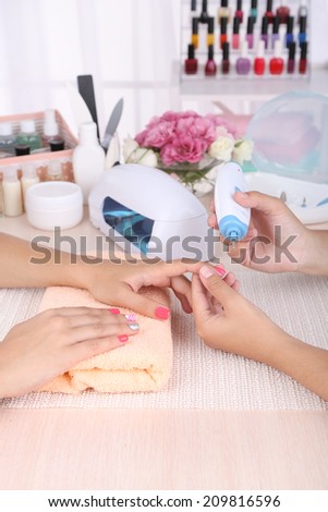 Young woman is getting manicure in beauty salon, close-up