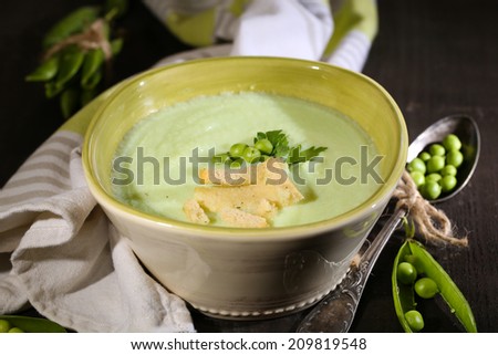 Tasty peas soup on wooden table with dark light