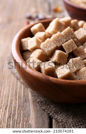 Brown sugar cubes, reed and crystal sugar in bowl on wooden background