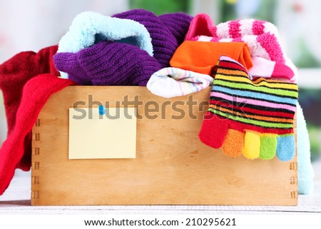 Multicoloured socks in box on a wooden table in front of the window