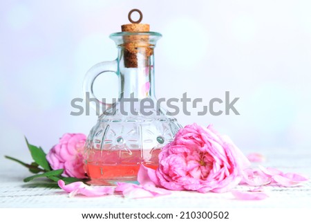 Rose oil in bottle on color wooden table, on light background
