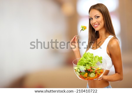 Beautiful young woman with salad on interior background