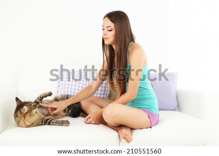 Beautiful young woman with cat sitting on sofa