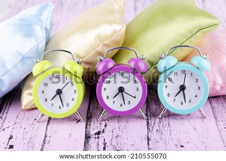 Plastic clocks on a silk pillows on wooden background