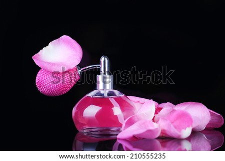 Perfume bottle with petals isolated on black