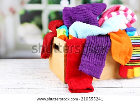 Multicoloured socks in a box on a wooden table in front of the window