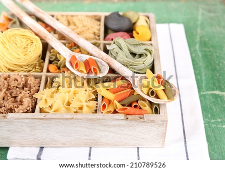 Colorful pasta in wooden box on wooden table background