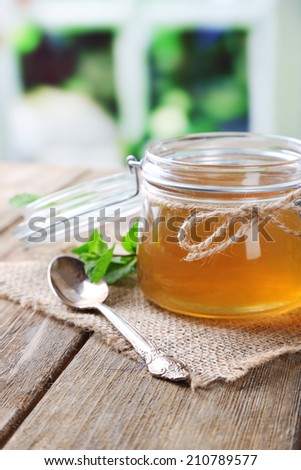 Homemade mint jelly in glass jar, on wooden table, on bright background