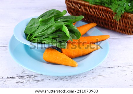 Carrots and sorrel on blue round plate on wooden background