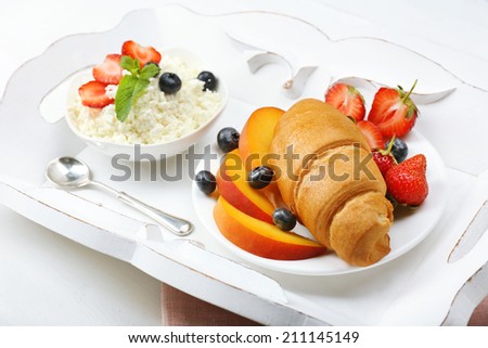 Delicious breakfast with croissant, cottage cheese and fruits