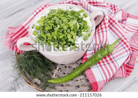 Pink round pan of cream with onion on a round wooden stand and soft napkin on wooden background