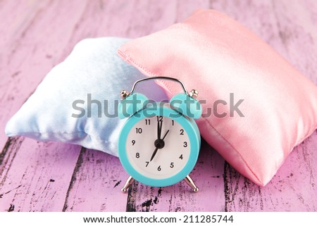 Plastic clock on a silk pillows on wooden background